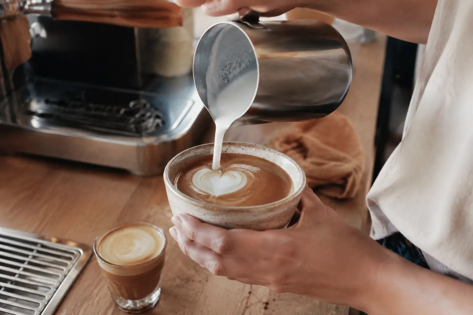 A home barista pouring microfoam into espresso
