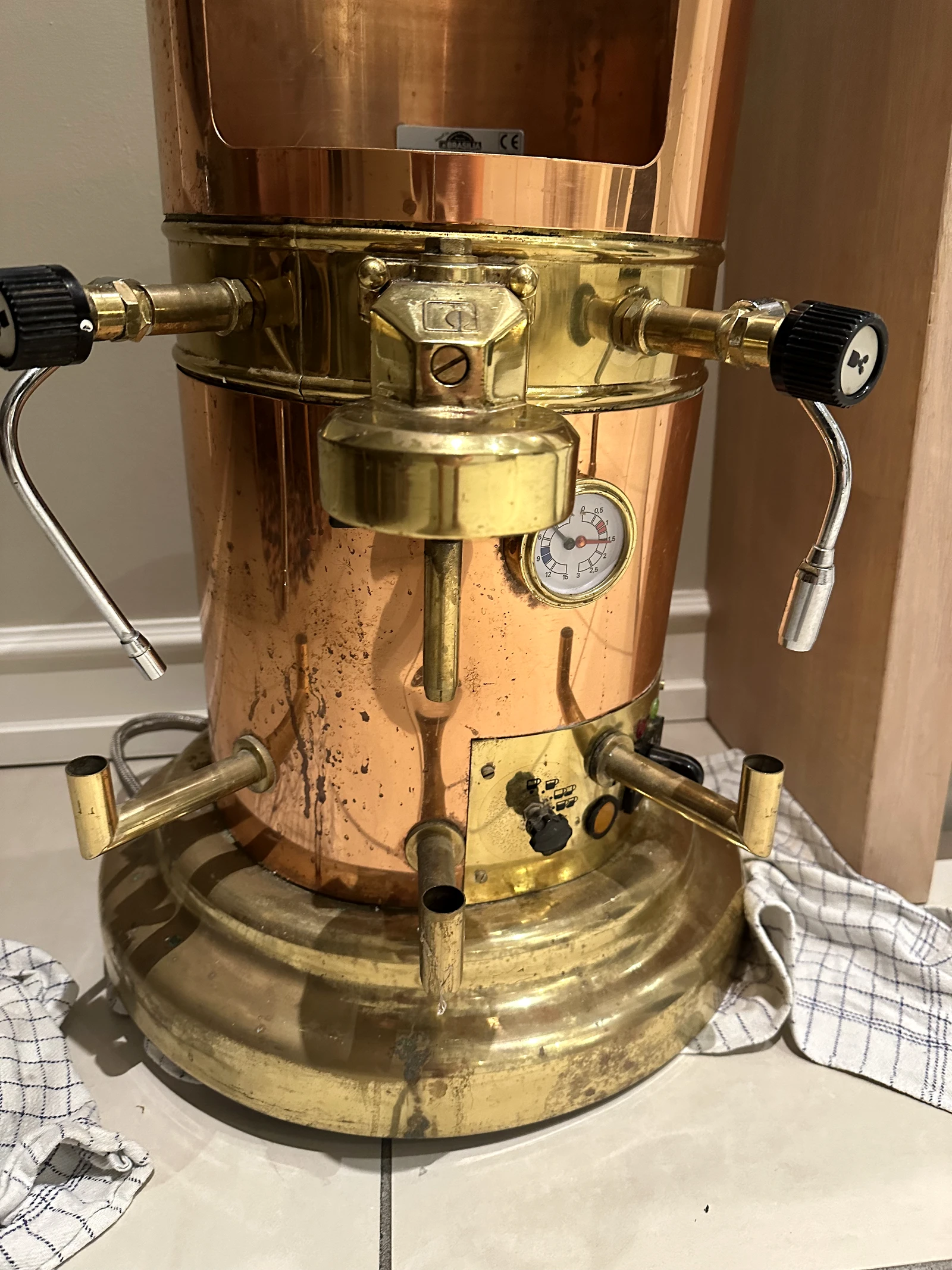 Close view of the vintage Brasilia espresso machine’s group, steam controls, gauge and patinated copper body